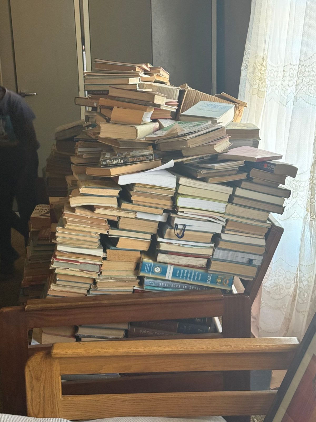 Stacks of donated second-hand books piled on a bench