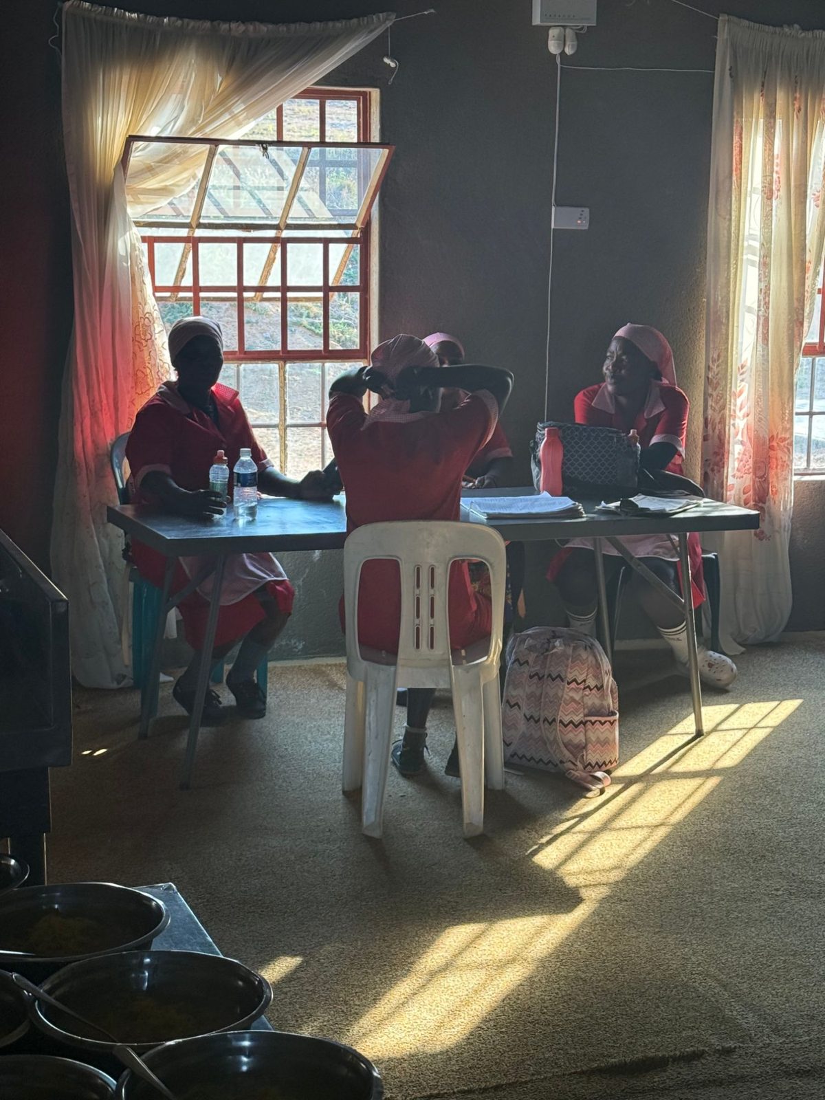 Care workers in red and pink uniforms at a table with their registers