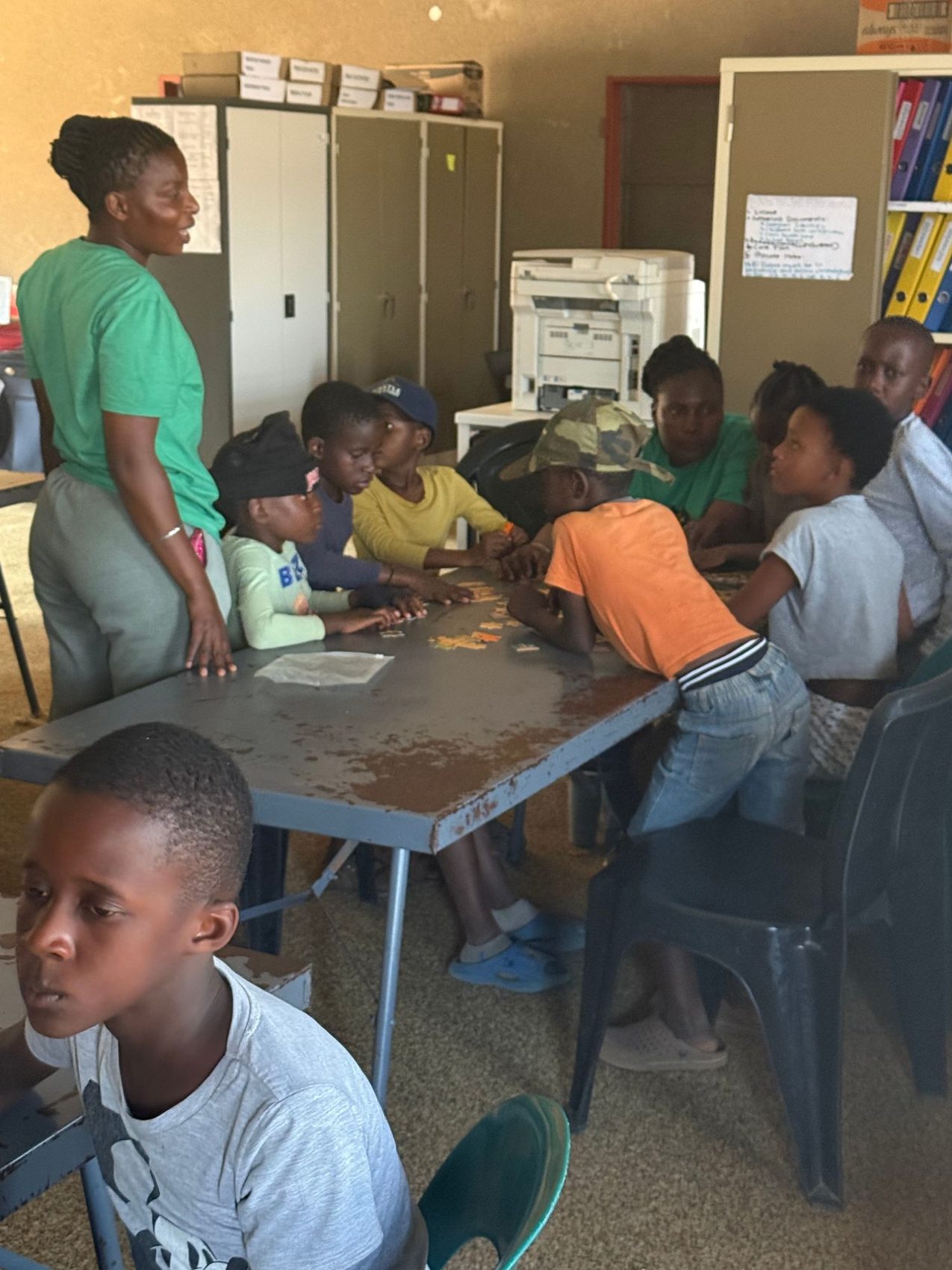 Children working through a puzzle at a table with two staff members