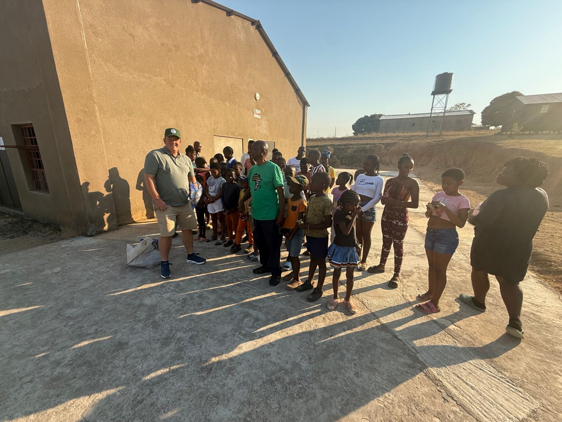 Sunstone Valley visiting the SizaBantwana care centre, standing with the manager and the children outside the hall